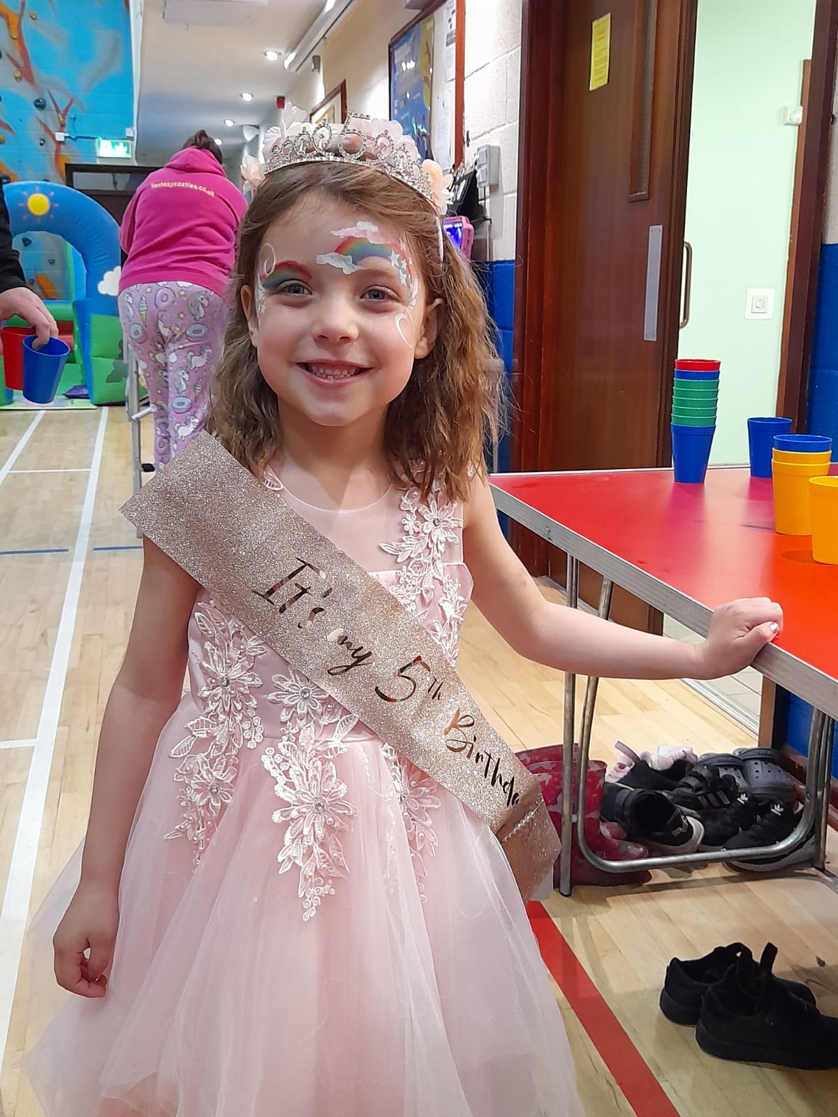 girl dressed as princes with rainbow face paint at birthday party