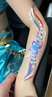 Girl with flowers painted on her arm at a party in Stafford