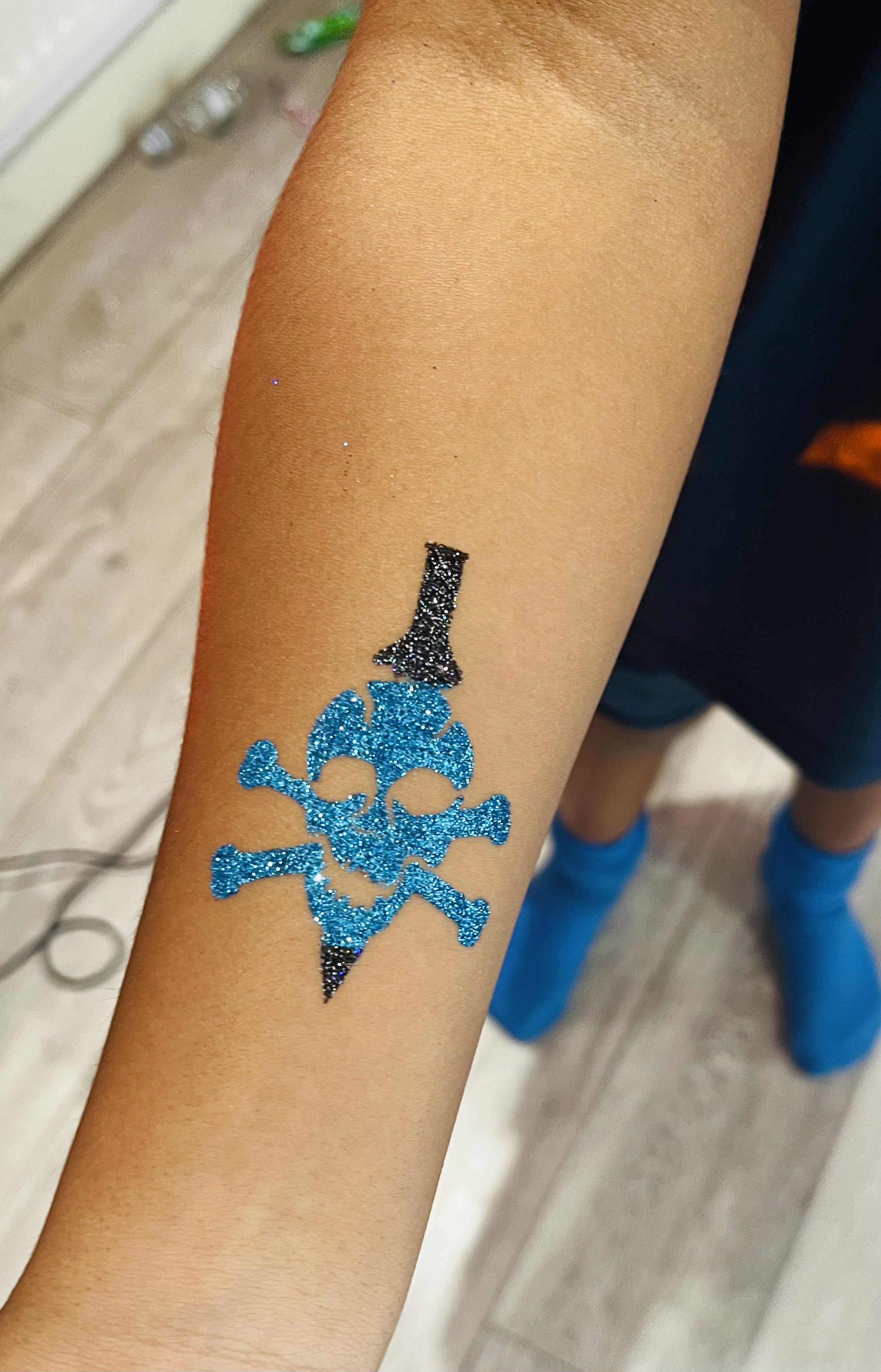 Skull tattoo on a childs arm in glitter